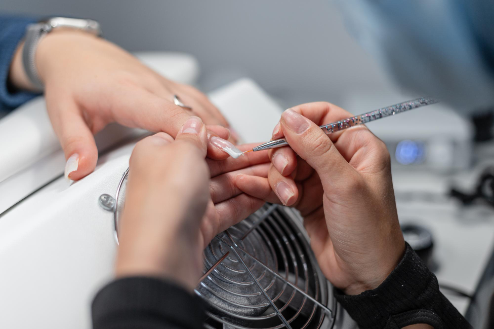 Tırnak şekillendirme ve bakım sürecinde estetisyen tarafından kalıcı oje uygulaması.